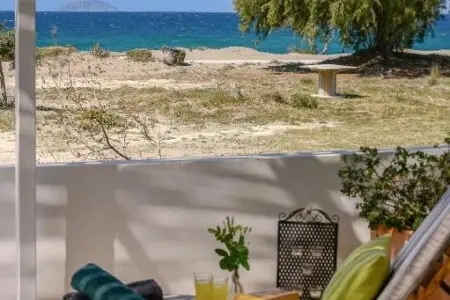 View of the sea from the patio of Paximadia Beachfront Apartment in Neo Kalamaki at sunset. The sky glows with warm colors, reflecting over the calm waters