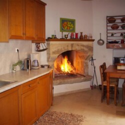 Cozy kitchen of Sior Nikoletos with a fireplace, offering traditional Cretan charm.