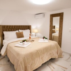 Cozy bedroom with a brown upholstered bed and soft lighting at Villa Virginia in Kalamaki, Crete.